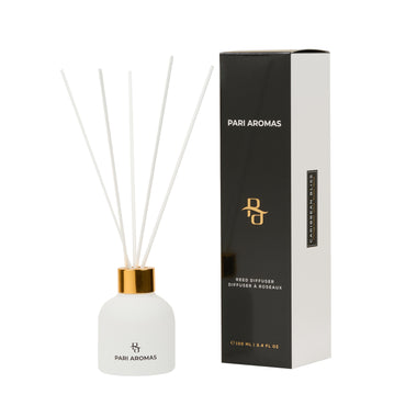 Caribbean Bliss reed diffuser with pomegranate, clove, and guaiac wood in a clear glass bottle with natural fragrance sticks
