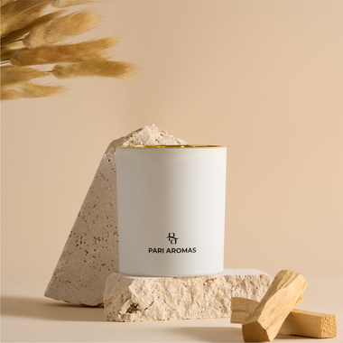 Hand-poured candle with smoky palo santo and cedar scent burning on driftwood tray with soft coastal lighting